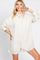 woman wearing a beige linen button-up romper with long sleeves and a collared neckline