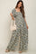 woman wearing a floral maternity jumpsuit with short puff sleeves and holding a woven bag