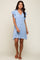 woman wearing a light blue button down mini dress with ruffle sleeves and frayed hem