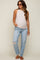 woman wearing a light pink ribbed maternity tank top and distressed light blue jeans, showing her baby bump