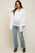 woman wearing a white oversized button-up shirt, a white tank top, and distressed jeans, showing her baby bump