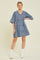 woman wearing a light blue denim tiered dress with bell sleeves and a v-neckline, paired with white ankle boots
