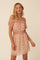 woman wearing a pink floral off-the-shoulder crop top and matching mini skirt with ruffle details
