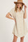 woman wearing a beige linen button-down shirt dress and a brown wide-brim hat