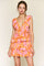 woman wearing a floral orange and pink tiered mini dress with a deep v-neckline and sleeveless design