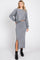 woman wearing a grey cropped long sleeve top and matching high-waisted skirt with side slits, styled with ankle boots