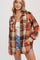 woman wearing an orange and cream plaid flannel shirt, styled with a white tank top and denim shorts