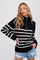 woman wearing a black and white striped quarter-zip sweater and distressed denim shorts