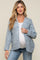 woman wearing a light blue maternity cardigan and a white top, showing her baby bump, paired with blue jeans