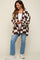 woman wearing a brown and white checked maternity cardigan over a white top and blue jeans, with a visible baby bump
