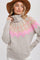 woman wearing a beige turtleneck fair isle sweater with pink and tan patterns and a brown wide-brimmed hat