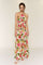 woman wearing a floral maxi dress with a halter neck and cut-out waist details, featuring vibrant pink and green colors