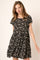 woman wearing a black short sleeve tiered mini dress with white daisy floral print