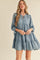 woman wearing a blue long sleeve tiered mini dress with a tie neckline and ruffled hem
