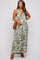 woman wearing a green floral maternity maxi dress and holding her baby bump, pairing with a woven bag and sandals