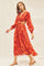 woman wearing orange and red floral maxi dress with waist cutouts and long puff sleeves