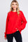 woman wearing a vibrant red oversized sweater with long sleeves and a ribbed hem, smiling at the camera