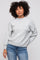 woman wearing a light gray oversized sweater with balloon sleeves paired with blue jeans