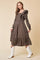 woman wearing a brown long sleeve dress with ruffle details and tiered skirt, paired with white cowboy boots