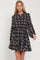 woman wearing a navy plaid long sleeve dress with a drawstring waist and flared skirt