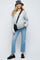 woman wearing a gray oversized maternity sweater and light blue cropped jeans with a black bucket hat and crossbody bag