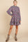 woman wearing a gray floral long sleeve dress with ruffle hem and frill details, paired with gray ankle boots