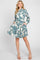 woman wearing a blue and cream floral print shirt dress with a ruffled hem and pockets