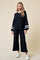 woman wearing a black lounge set with white stripes on the sleeves and pants, paired with white sneakers