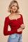 woman wearing a red ribbed long sleeve top with a square neckline and high-waisted denim jeans