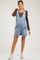 woman wearing a light blue maternity denim overall shorts and a brown long sleeve top, showcasing her baby bump