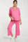 woman wearing a pink maternity top and matching pants, relaxed fit with a v-neck and loose sleeves, showcasing a baby bump