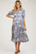 woman wearing a blue and cream patterned maternity dress with short puff sleeves and a flowy skirt, showcasing her baby bump