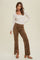 woman wearing a cream long sleeve henley top and brown suede flared pants with side slits