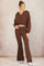 woman wearing a brown cropped hooded sweatshirt and matching flared pants with side slits