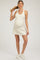 woman wearing a light beige maternity dress with a fitted bodice and a flared skirt, showcasing her baby bump