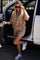 woman wearing a beige short set with a loose fit and standing next to a car, paired with white sneakers and sunglasses