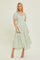 woman wearing a green and white floral print maxi dress with puff sleeves and tiered skirt