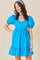 woman wearing a bright blue puff sleeve mini dress with a ruffled hem and button details