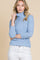 woman wearing a light blue fitted turtleneck sweater with three-quarter sleeves and white jeans