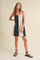 woman wearing a black and cream color block sleeveless mini dress and black strappy sandals