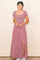woman wearing a red floral maxi dress with short sleeves and a thigh-high slit, standing against a neutral background