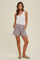 woman wearing a light gray sleeveless top and matching shorts with pockets, standing on a neutral background
