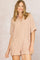 woman wearing a light pink short-sleeve collared romper with two front pockets