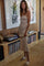 woman wearing a beige ribbed midi dress and fuzzy slides, standing in a living room with vinyl records in the background