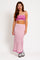 woman wearing a pink ribbed crop top and matching long skirt with a fitted silhouette and white sneakers
