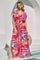 woman wearing a vibrant pink and multi-colored floral maxi dress with short sleeves and a tie waist detail