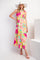 woman wearing a floral maxi dress in pink, yellow, and green with tiered ruffles and a wide-brimmed hat