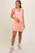 woman wearing a light pink maternity active dress, showcasing her baby bump, paired with sneakers
