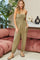 woman wearing a strapless olive green jumpsuit with pockets and relaxed fit, standing in a cozy indoor setting