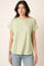 woman wearing a light green short sleeve top with rolled sleeves and relaxed fit, paired with light blue jeans